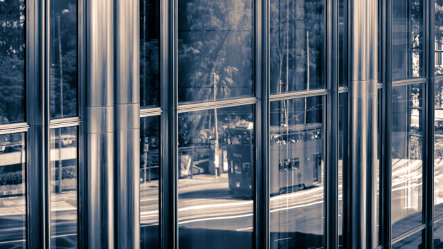 Modern building facade with aluminium-clad windows and reflective surfaces, illustrating contemporary architectural design.